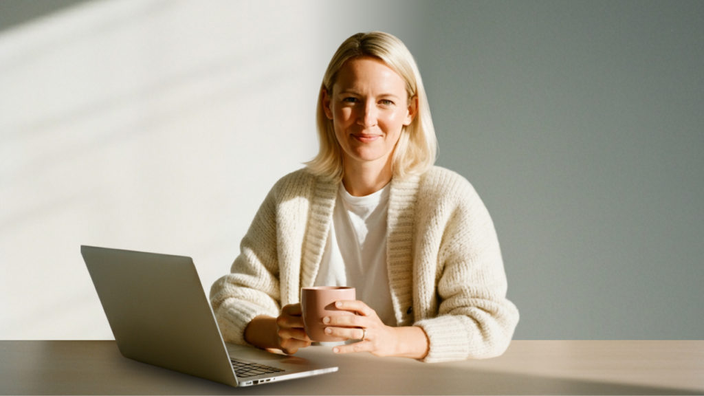 Dame som er fornøyd med arbeidsrutiner, smiler til kamera med kaffekopp